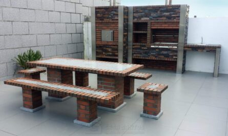 Aménagement moderne d'une cuisine extérieure en briques rouges et pierres sombres avec four à pizza, barbecue intégré et table de jardin assortie