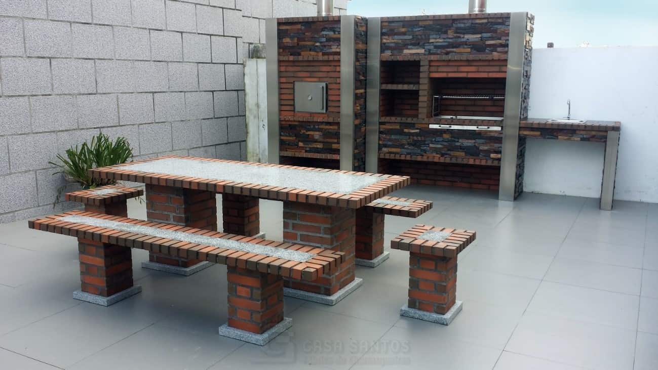 Aménagement moderne d'une cuisine extérieure en briques rouges et pierres sombres avec four à pizza, barbecue intégré et table de jardin assortie