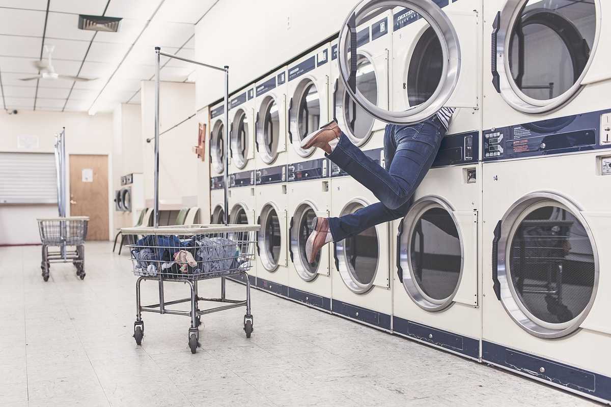 Une personne sort d'une machine à laver dans une blanchisserie Une personne sort d'une machine à laver dans une blanchisserie