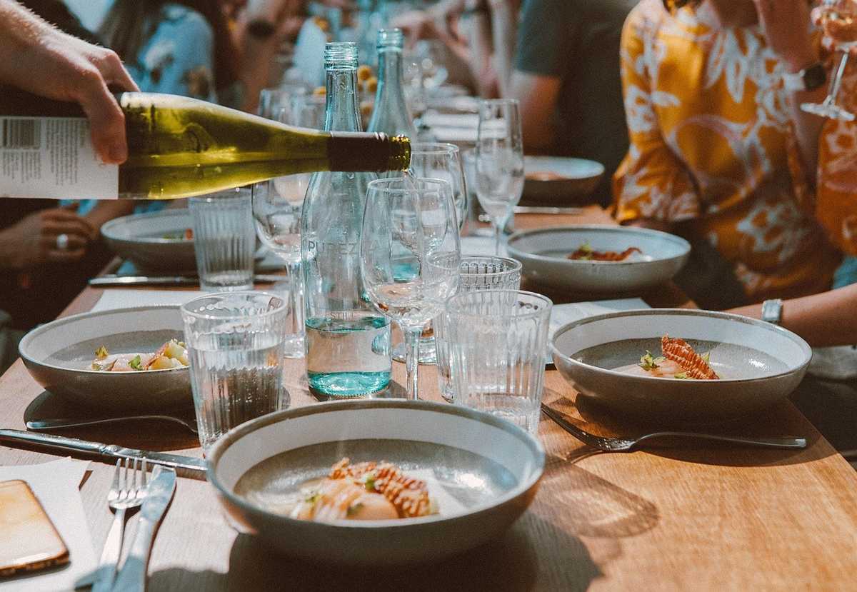 Groupe de personnes assises autour d'une table, repas en cours, verres et plats sur la table