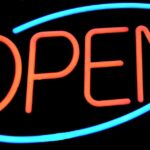 Lumière néon orange formant le mot OPEN, encadré par deux ovales bleus