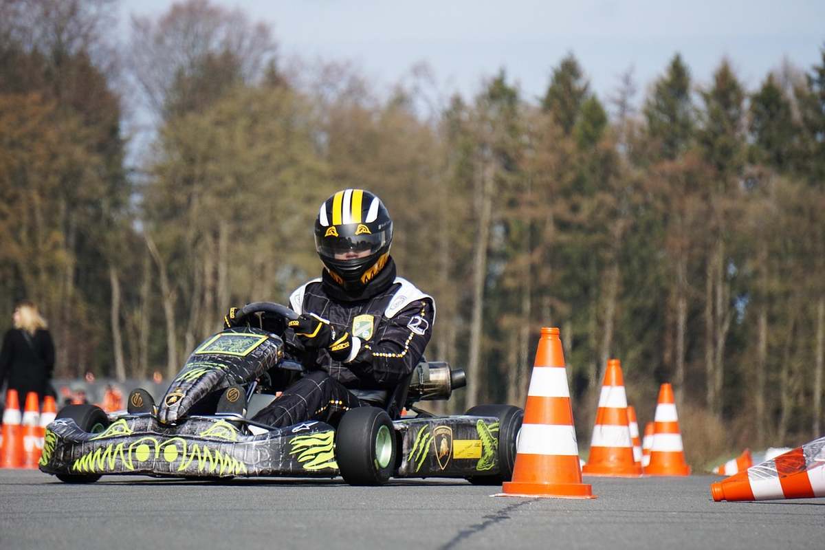 Un coureur en casque pilote un kart sur un circuit avec cônes