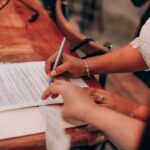 Mains écrivant sur un document à une table en bois