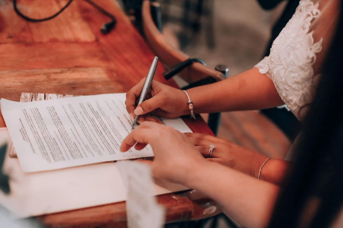 Mains écrivant sur un document à une table en bois