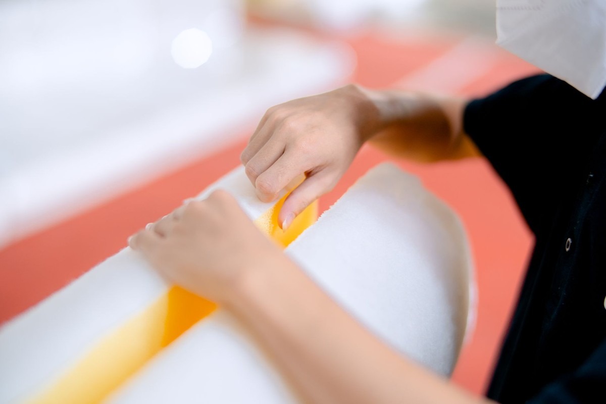 Des mains appliquent un cutter jaune sur un rouleau blanc Des mains appliquent un cutter jaune sur un rouleau blanc