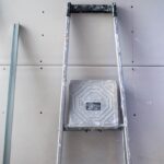 Un escalier et un marche‑pied posés contre un mur de plaques sèches