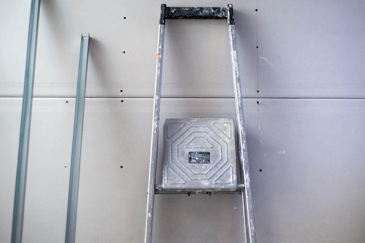 Un escalier et un marche‑pied posés contre un mur de plaques sèches
